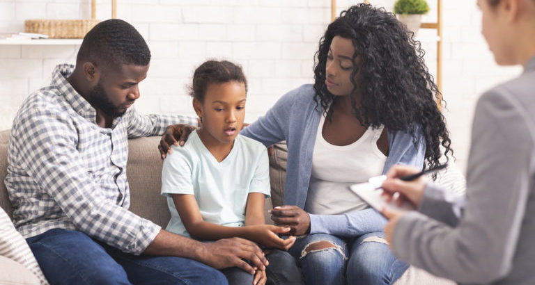Bipolar Disorder In Children Concept. Little african american girl and her parents at reception of psychologist, kid sharing her feelings with doctor